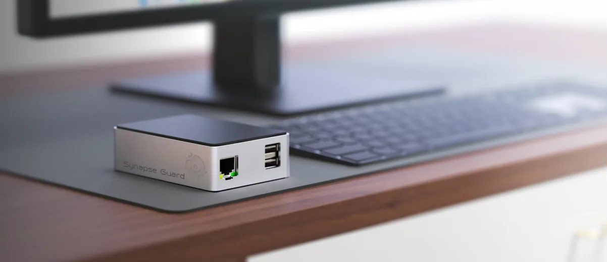 SynapseGuard hardware prototype positioned beside a workstation